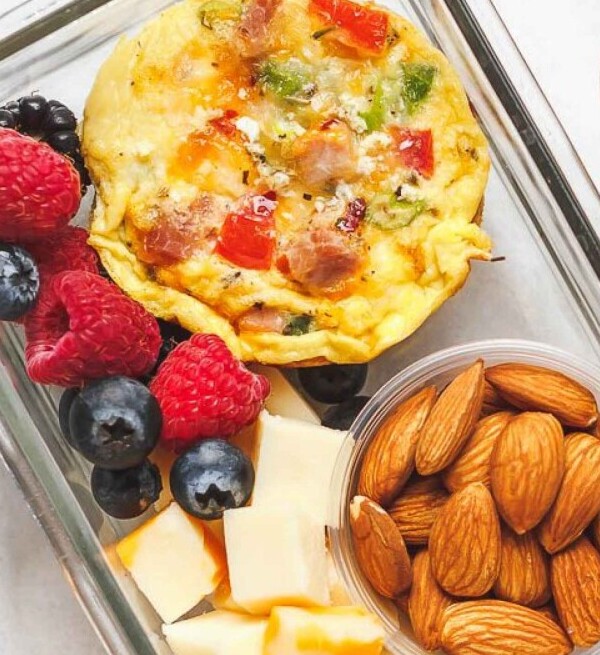 “Keto breakfast meal prep with veggie egg muffin, almonds, and hot sauce in glass container”